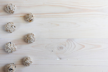 Granola energy bites with nuts, seeds, dry cranberries and honey in coconut flakes on a light background, flat lay, free space for text, horizontal orientation