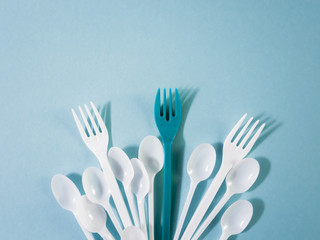 Plastic dishes, disposable tableware, plates, glasses, spoons, forks on a blue background. Caring for the environment. The problem is recycling. Reuse, safe planet, environmental concept. Trash.