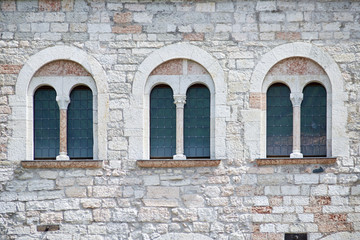 Three Italian antique windows on the old castle stone wall facade