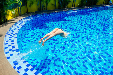 beautiful young armless woman training to swim in pool at tropical resort