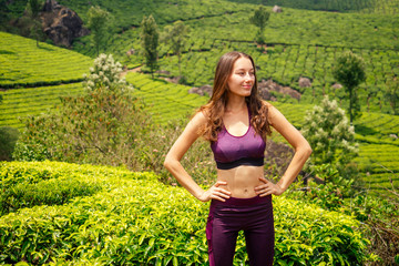 Naklejka na ściany i meble young tourist girl with a backpack enjoying a good morning in tea plantations in India Munnar Kerala