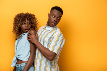 side view of scared african american couple looking away on yellow colorful background