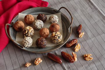 dried fruit sweets, for a healthy diet, homemade energy balls help the body fight viruses,candies are in a metal, caramic dish on gray, white textile background, horizontai frame
