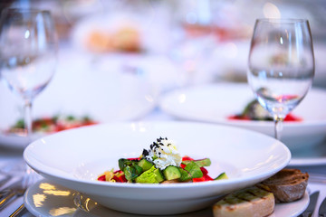White plate with salad on a restaurant background.