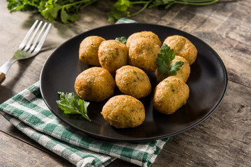Traditional cod fritters with garlic and parsley on wooden table