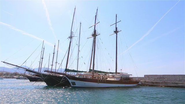 beautiful old yachts are anchored in the marina, yachts moored to the shore, two-masted yachts of millionaires, the life of rich people, yachts against the blue sky