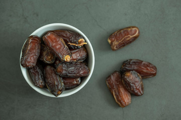 Raw date fruit ready to eat in porcelain bowl on concrete background. Traditional, delicious and healthy ramadan food. Top view, flat lay.