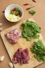 Fresh Ingredients of Pad Kra Pao (Thai food). Beef,Chicken, Thai Holy Basil, Garlic and Red Hot Chilli on wooden cutting board- Stock Photo