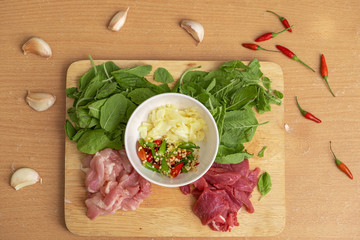 Fresh Ingredients of Pad Kra Pao (Thai food). Beef,Chicken, Thai Holy Basil, Garlic and Red Hot Chilli on wooden cutting board- Stock Photo