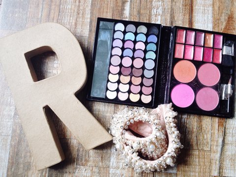 High Angle View Of Letter R With Make-up Kit On Table