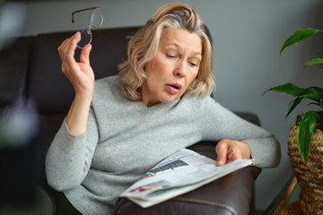 Shocked woman reading newspaper. Bad news.