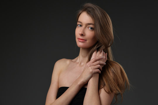 Portrait of a beautiful girl in a black dress on a gray background