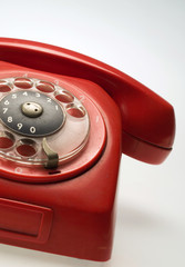 A partial frontal view of a red vintage old rotary phone.