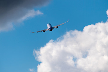 Fototapeta na wymiar Airplane in the sky. Aircraft between clouds backside shot