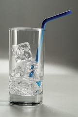 A glass filled with ice and a straw.