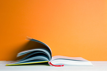 book on a white table, orange background
