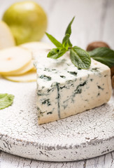 Segment of blue mould cheese - Gorgonzola with pear and walnuts on wooden board.  Top view