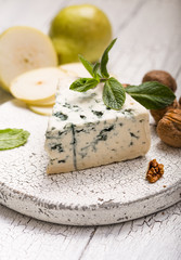 Segment of blue mould cheese - Gorgonzola with pear and walnuts on wooden board.  Top view