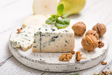 Segment of blue mould cheese - Gorgonzola with pear and walnuts on wooden board.  Top view