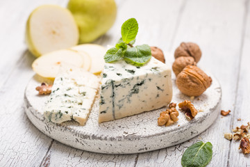 Segment of blue mould cheese - Gorgonzola with pear and walnuts on wooden board.  Top view