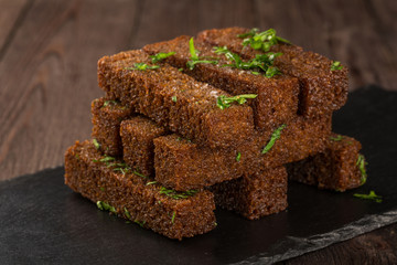 Fried croutons with garlic on a black board. Beer snack.
