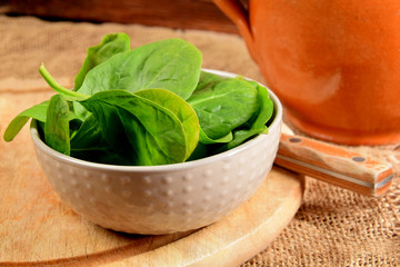 spinach leaves in a bowl on a wooden kitchen board