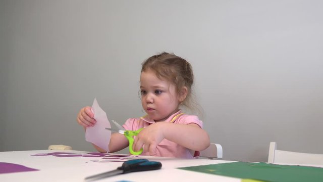 the child cuts colored paper with scissors