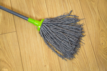 MOP for wet cleaning on the background of brown laminate in the apartment, care household inventory.