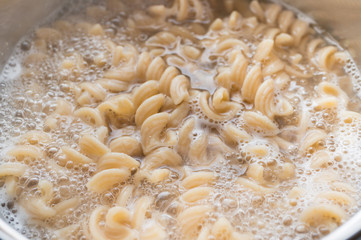 Fototapeta na wymiar Whole grain pasta in a pan with boiling water and a spoon. Cooking healthy food.