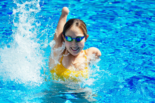 beautiful young armless woman training to swim in pool at tropical resort