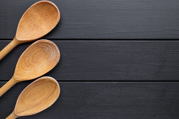 Wooden spoons isolated on black background.Vintage style. Top view, copy space.