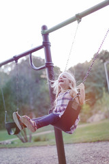 Portrait of happy little girl riding a swing