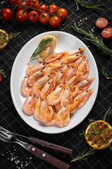 Boiled king prawns on a white plate. Decorated with a slice of lemon.