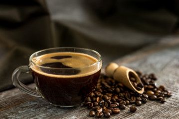 Warm cup of aromatic tasty healthy coffee against a dark background. coffee beans