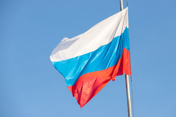 Tricolor clean Russia flag on a blue sky background. waving flag on a pillar from the wind