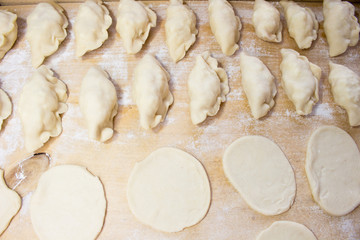National Russian cuisine. Pierogi or pyrohy, vareniki, served with cottage cheese and potatoes on board.  Raw dumplings made of dough in handmade flour