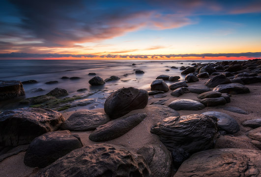 Amazing colorful seascape with rocky beach at sunrise