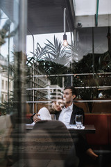 A couple in love sitting in a cafe. Photo taken through the glass of the restaurant