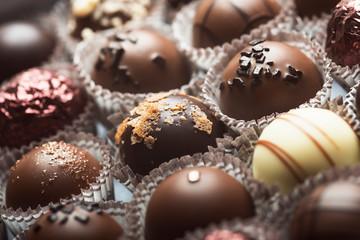 Mixed luxury dark and milk chocolate truffles. Assorted delicious handmade chocolate pralines in a row. Full frame background. Studio shot. Close-up