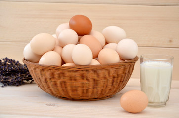 rustic still life basket with eggs and glass of milk on wooden background