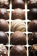 Mixed luxury dark and milk chocolate truffles. Assorted delicious handmade chocolate pralines in a row. Full frame background. Studio shot. Close-up