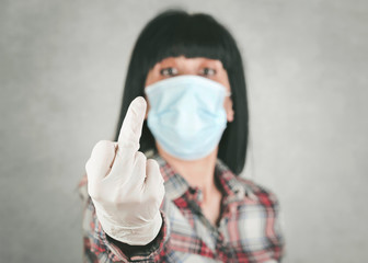 young woman wearing medical mask insulting with finger,background blur