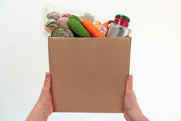 Food delivery service - male hands with a box of fresh food on a white background with copy space. Donation box.