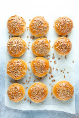 Fototapeta na wymiar Hot fresh homemade buns sprinkled with seeds. Top view
