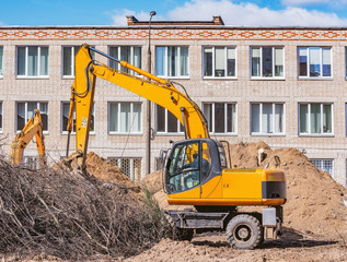 Obraz premium Excavator digs a hole on the construction site.