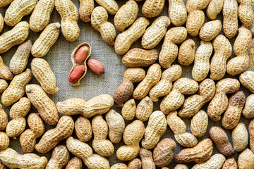Background of unshelled peanuts and a few peeled nuts.