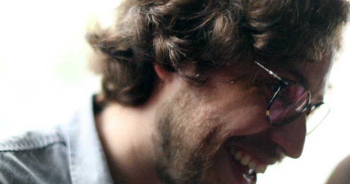 Happy young man drinking beer laughing and smiling talking to friends