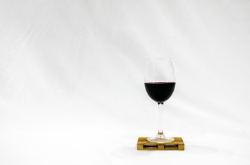 Glass of wine sits on the pallete in white background. Blank space image. Deliveries and trasnportation of wine.