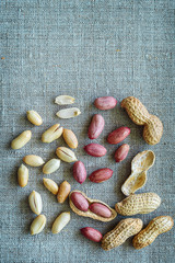 Whole and peeled peanuts lie on a gray burlap