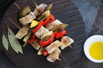 Baked greek codfish souvlaki on a black wooden serving board, view from above, horizontal shot